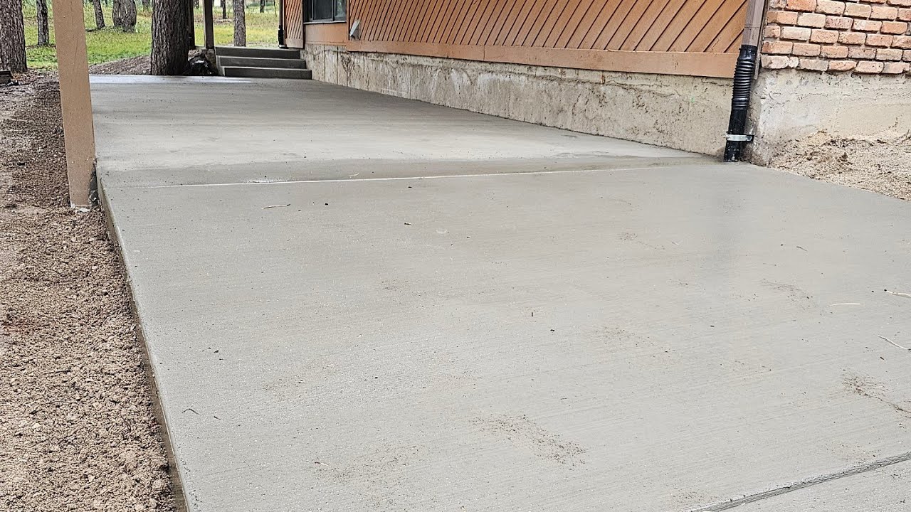 Concrete driveway with a patio, steps, and sidewalk.