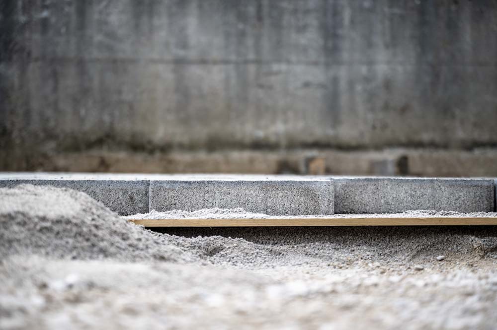 "Concrete slab being poured and smoothed by construction workers on a leveled ground surface.