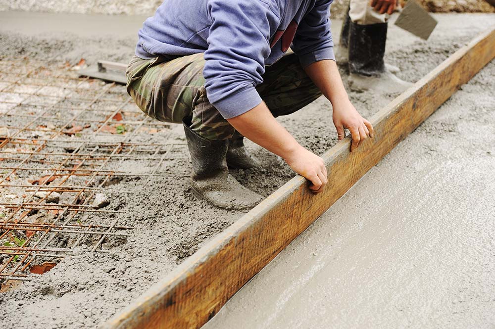 Professional concrete contractor finishing a concrete slab on a construction site.